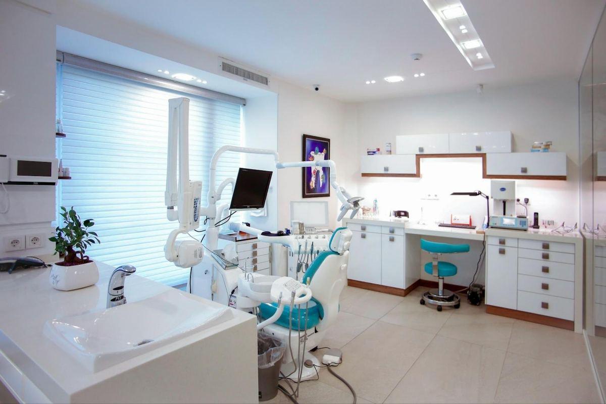 A bright, modern dental clinic with a treatment chair, intraoral X-ray unit and monitor