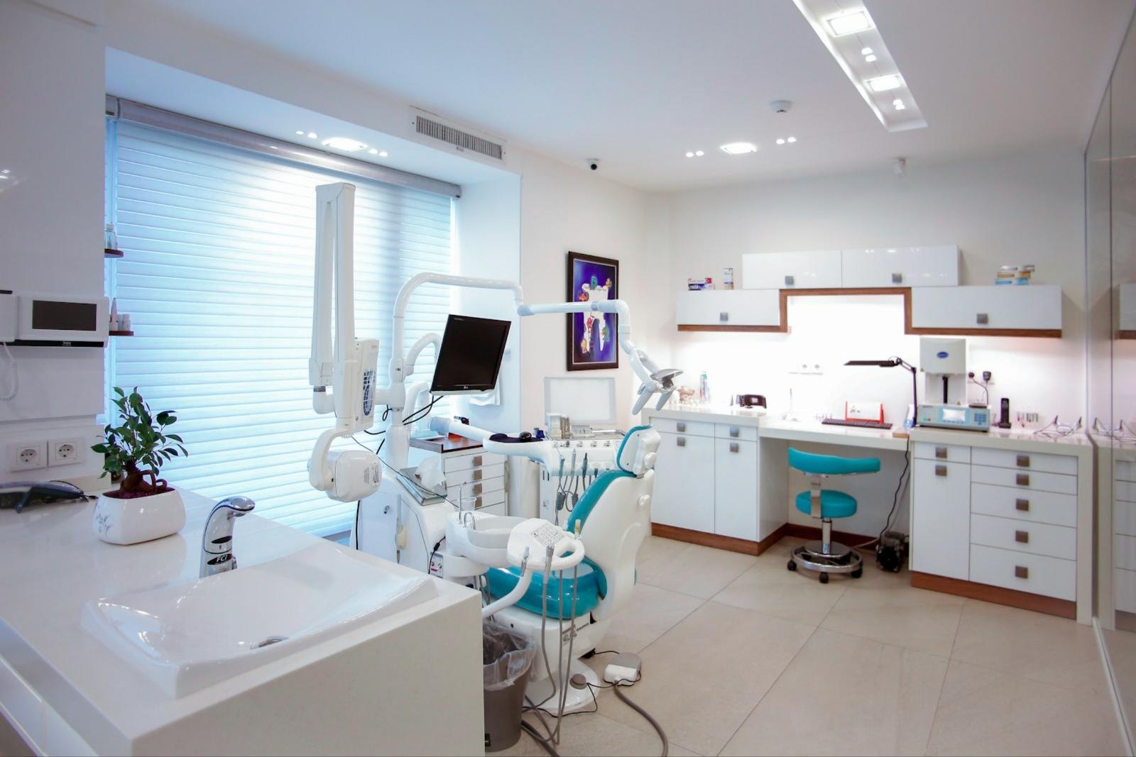 A bright, modern dental clinic with a treatment chair, intraoral X-ray unit and monitor